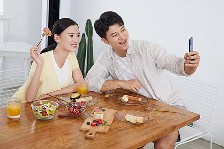 年轻情侣在餐厅用智能手机自拍图片