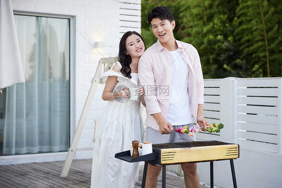 年轻情侣在别墅外做烧烤图片
