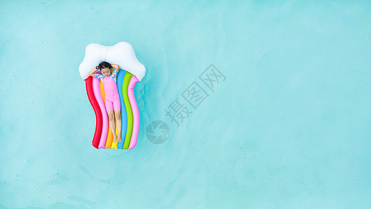 儿童小女孩躺在泳池彩虹气垫床上图片