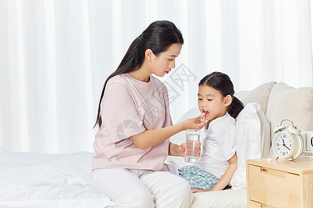 妈妈照顾生病女儿喝水吃药高清图片