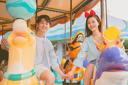 情侣陪伴游乐场游玩坐海洋旋转木马图片素材