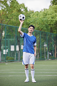 手举足球的男性运动员图片