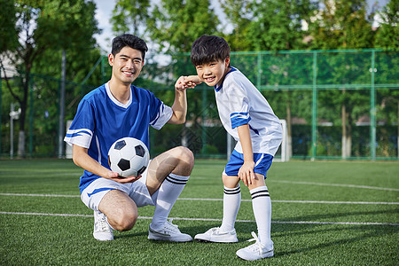 教练和男孩在足球场踢球形象图片