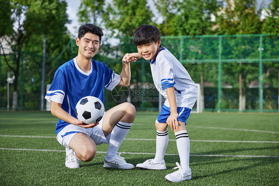 教练和男孩在足球场踢球形象图片