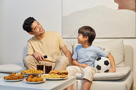 在家看足球赛爸爸和儿子坐沙发上开心看世界杯背景