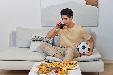年轻男性在家吃夜宵看球赛图片