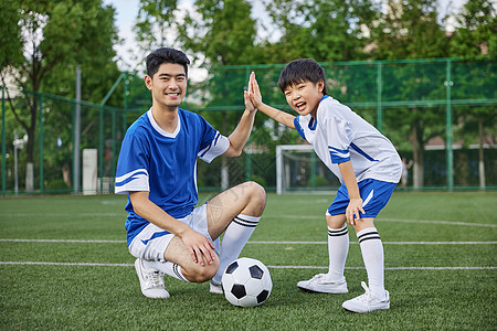 足球教练和男孩在足球场踢球形象图片