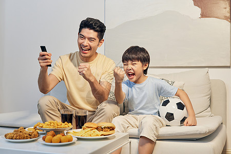 爸爸和儿子居家看比赛庆祝胜利图片