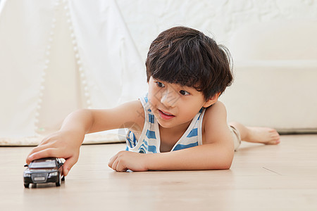 小汽车拖运小男孩趴在地板上玩小汽车背景