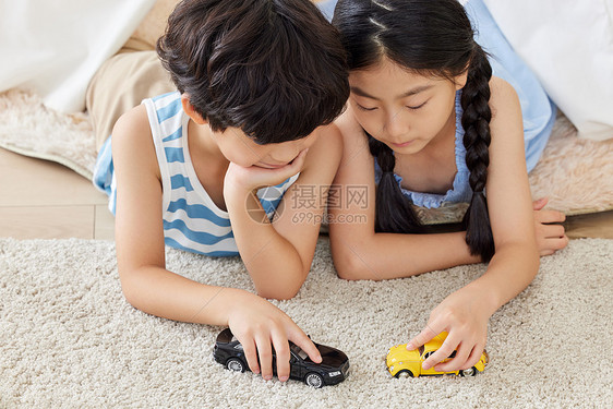 姐弟俩趴在地毯上玩汽车模型图片