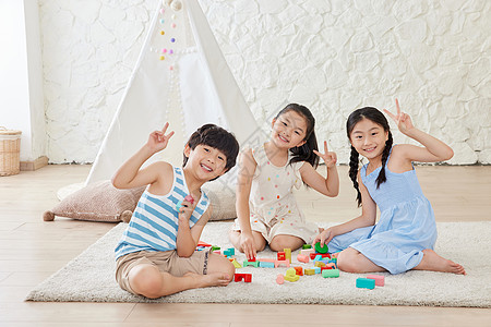 孩子游戏姐弟三人在地毯上堆积木背景
