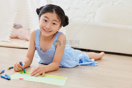小女孩趴在地板上画画图片