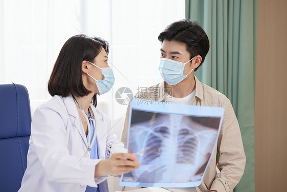 医院里医生拿着x光片与病人交流图片