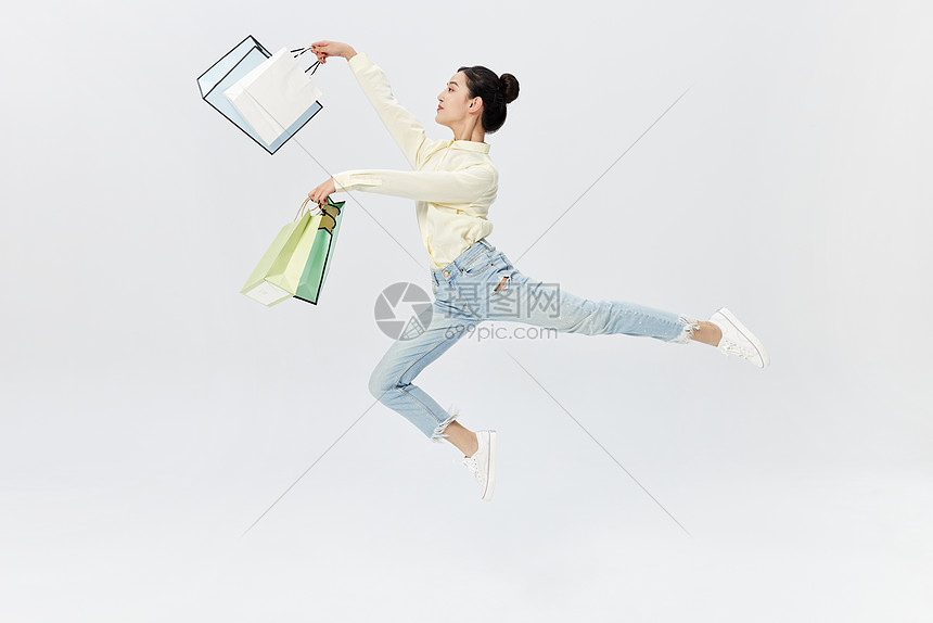 手拿购物带跳跃起舞的女性图片