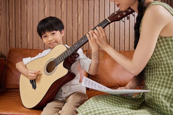 音乐教师教小男孩学生弹吉他图片