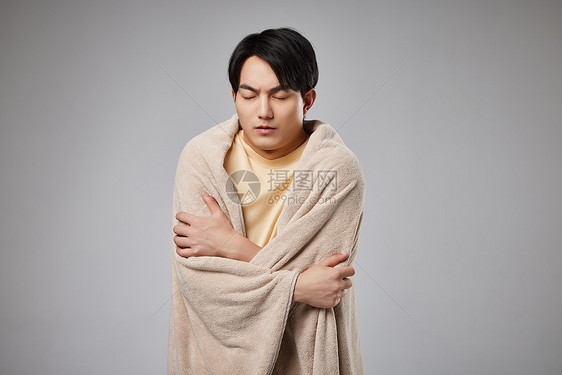 裹毯子取暖的青年男性图片