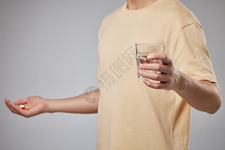 手拿水杯喝水吃药的男性特写图片