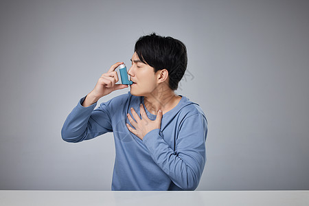 呼气年轻男性使用哮喘吸入器背景