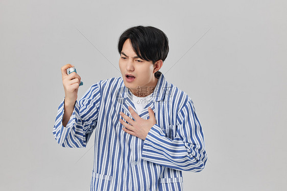 男性病患手拿哮喘吸入器图片