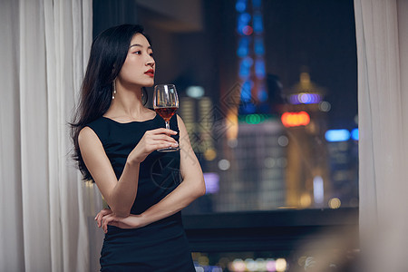 气质美女夜晚端着红酒杯站在窗前图片