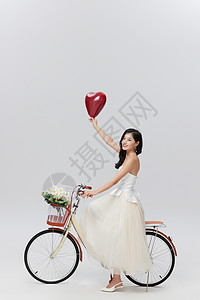 手拿气球情侣手拿爱心骑自行车的年轻女性背景
