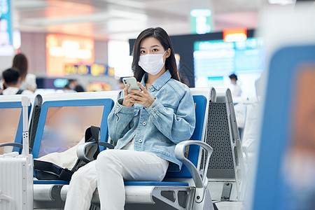 机场候机火车候车厅戴口罩的女性使用手机背景