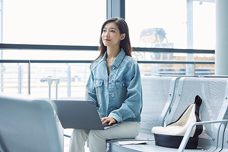 女性旅行出游在机场使用笔记本电脑图片