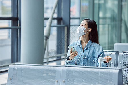 机场候机厅戴口罩的女性看手机图片