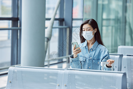 机场候机厅戴口罩的女性看手机图片