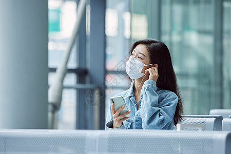 机场候机厅戴口罩的女性看手机图片