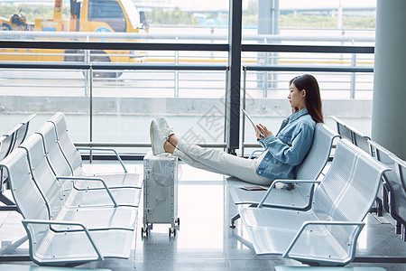 女性坐在机场候机厅使用平板电脑图片