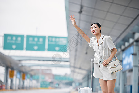 女性站在路边伸手拦车打招呼高清图片