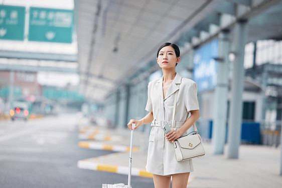 拉着行李箱焦急等车的商务女性图片