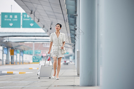 拉着行李走在机场外的职场女性图片