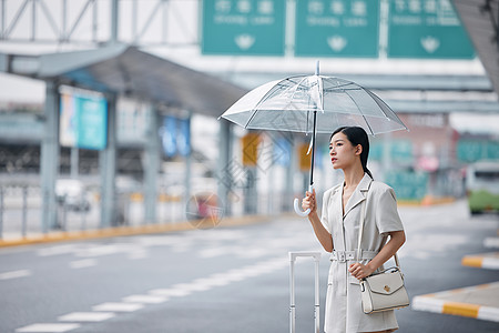 撑着伞在路边打车的商务女性图片