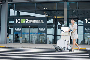 推着行李箱走在机场外的商务女性图片