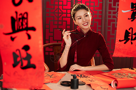 春节喜庆福字旗袍美女拿着毛笔面带微笑背景