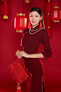 拿着中国结微笑的穿旗袍的年轻女子图片