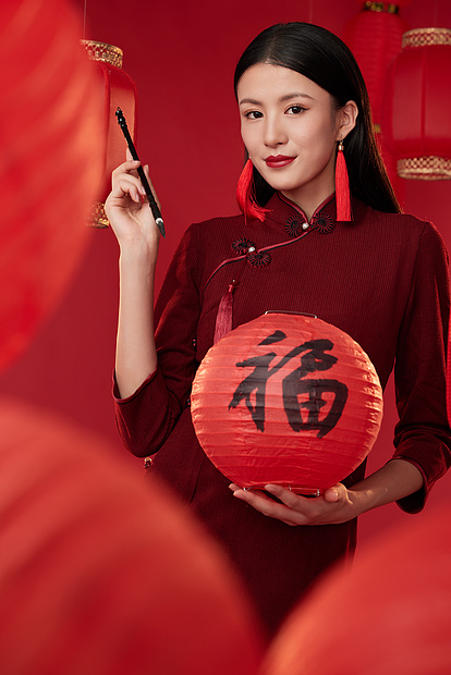 拿着福字灯笼和毛笔的年轻旗袍女性