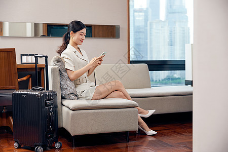 坐在酒店沙发上玩手机的商务女性图片