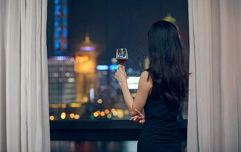 美女拿着红酒杯站在窗前背影图片