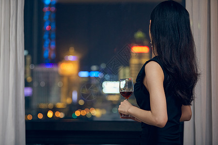 夜晚美女喝酒气质美女夜晚端着红酒杯背影背景
