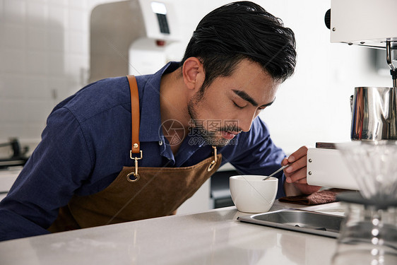 男性咖啡师低头闻刚冲好的咖啡图片