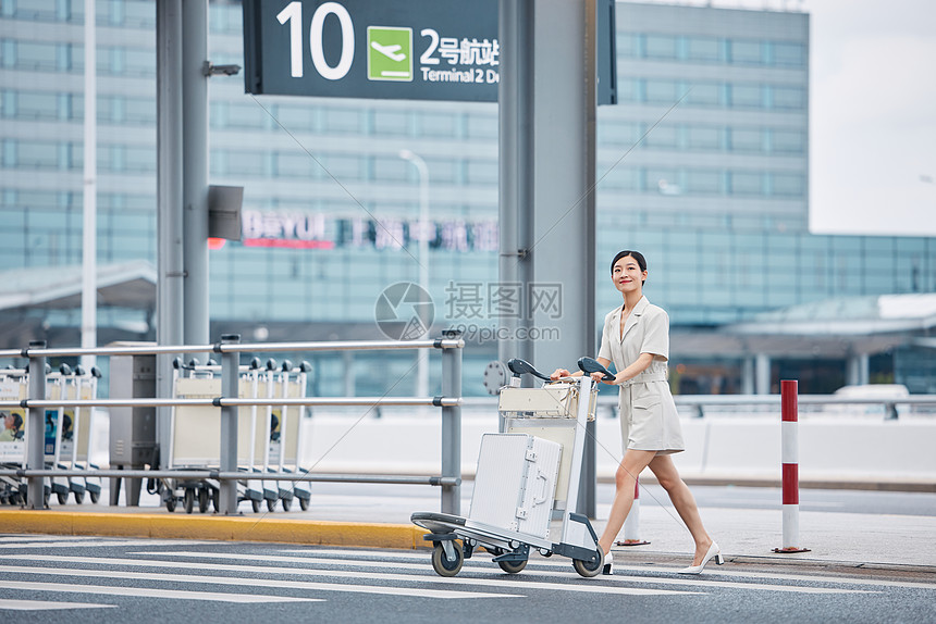 商务女性推行李箱过斑马线图片