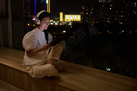 独居女性夜晚在窗边听歌图片