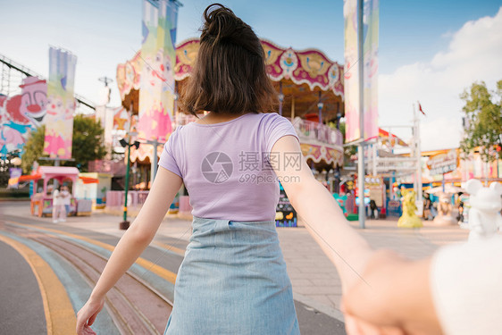 牵着男朋友手奔向游乐场的年轻女孩背影图片