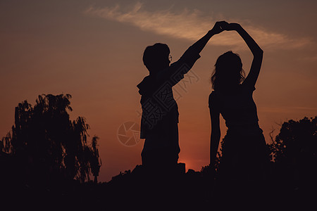 情侣相拥舞蹈夕阳下牵手舞蹈的情侣剪影背景