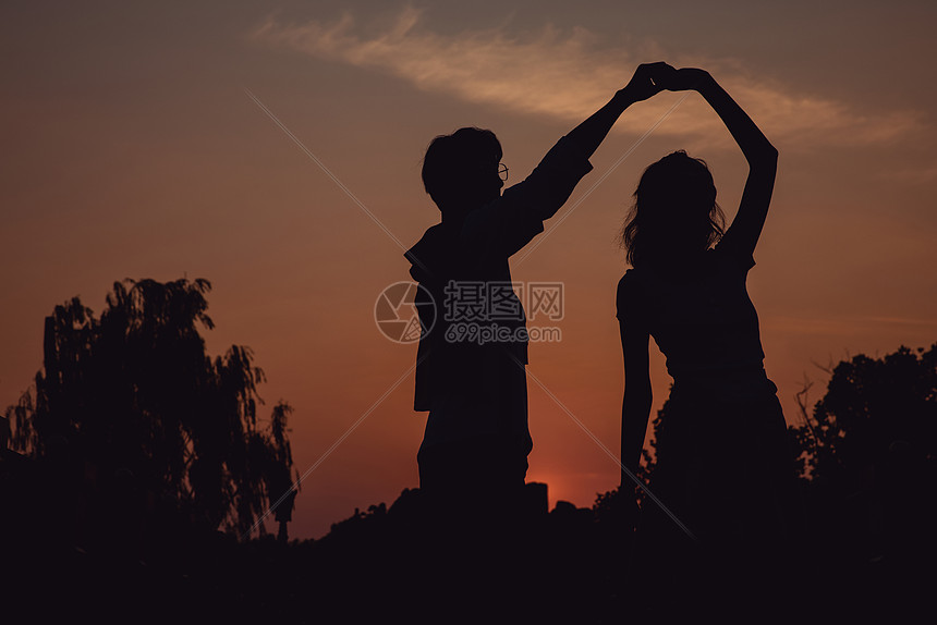 夕阳下牵手舞蹈的情侣剪影图片