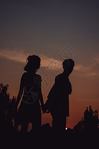 夕阳下牵手漫步的情侣剪影背景图片
