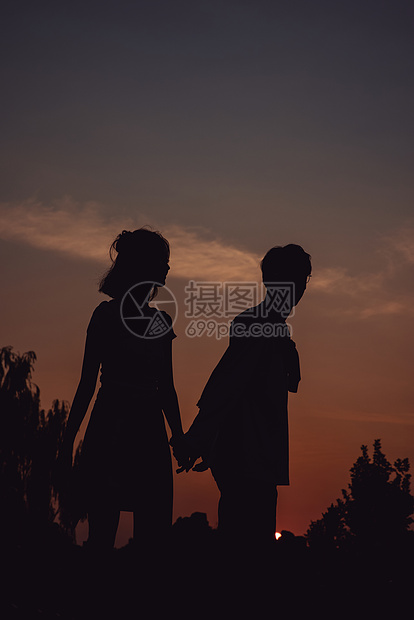 夕阳下牵手漫步的情侣剪影图片